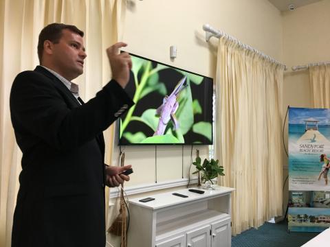Presenter speaking in front of a screen showing a photo of a Conception Bank silver boa